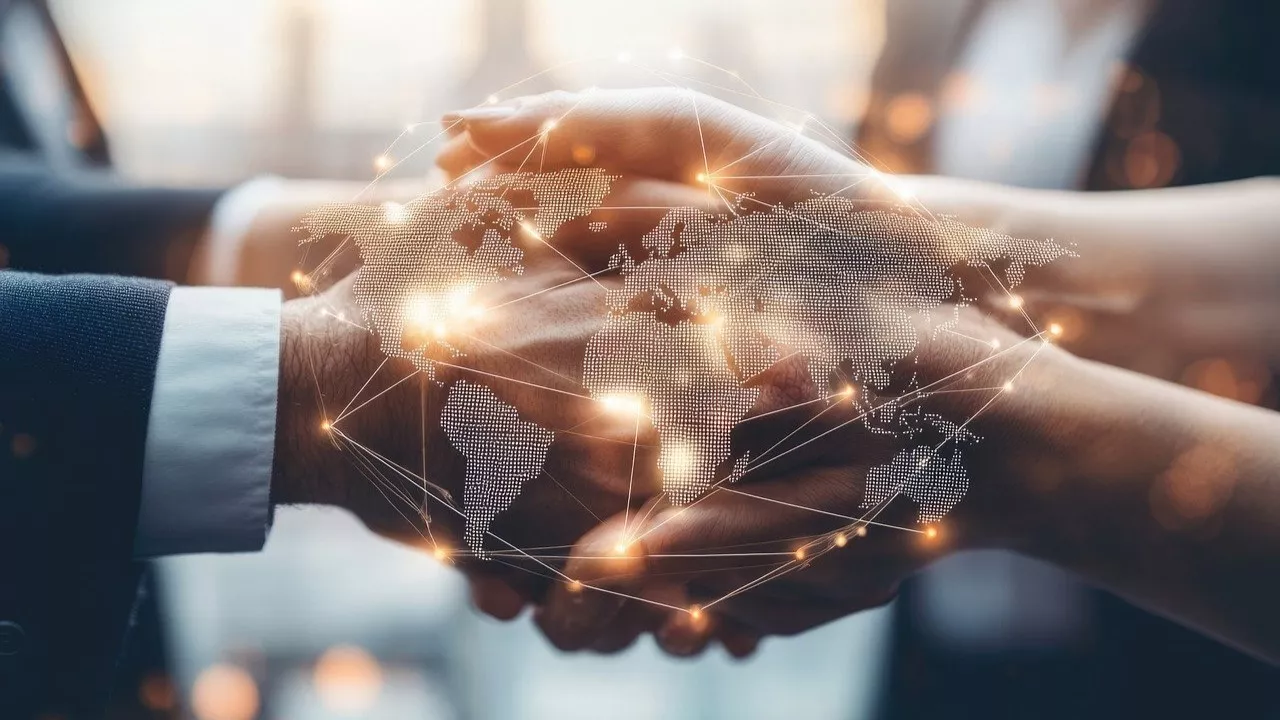 overlay of a world map on a image of two people shaking hands, signifying building global connections.