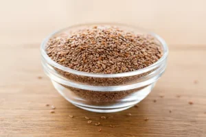 psyllium husk seads in a glass bowl on a wooden table.
